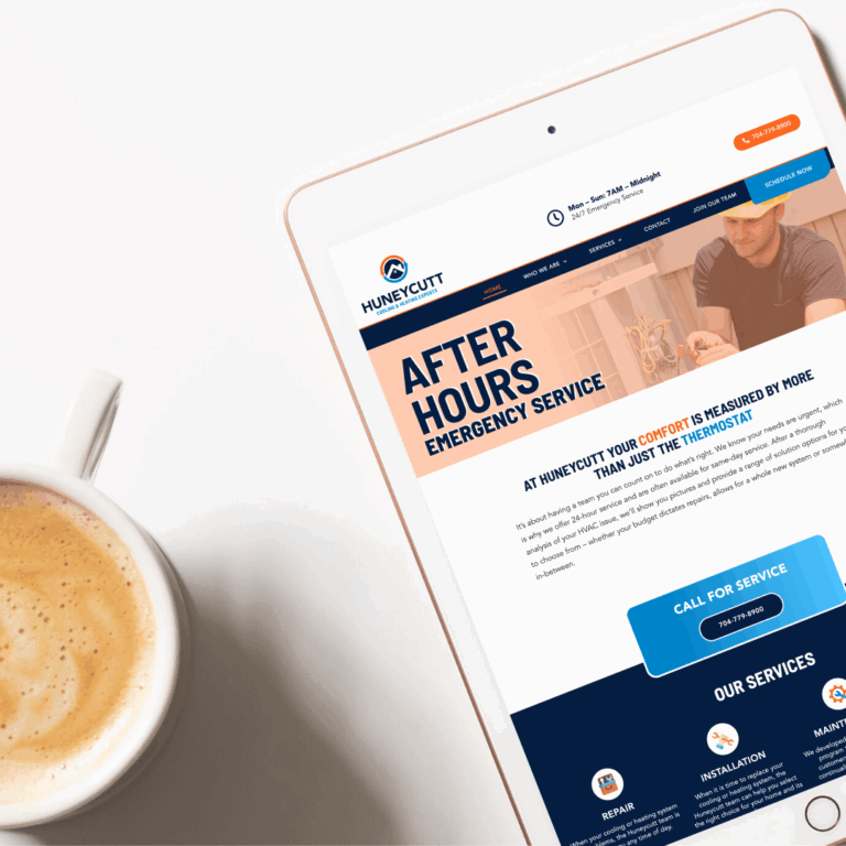 Tablet displaying Huneycutt HVAC custom website design next to coffee mug.