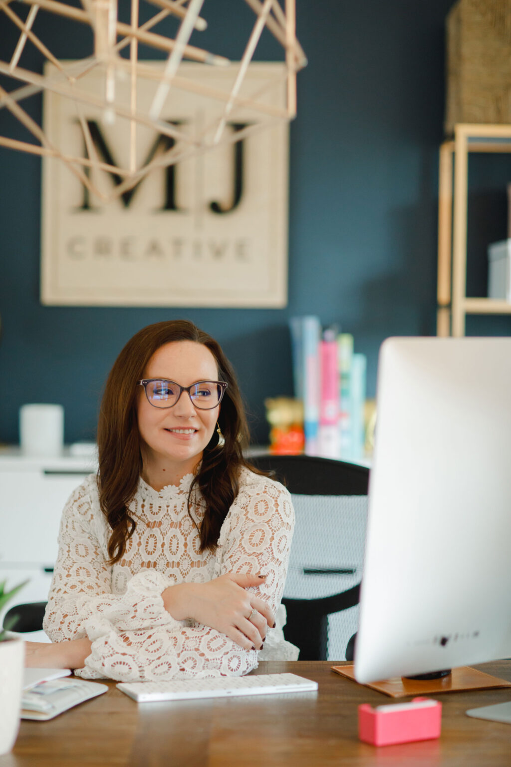 Michelle Jones smiling at imac sitting at desk in web design offices.