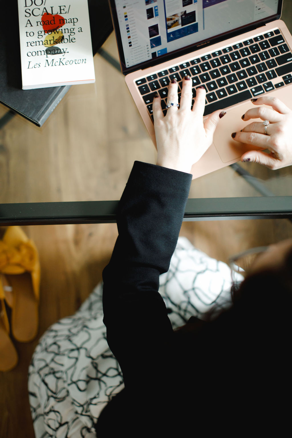 Person typing on laptop beside business book